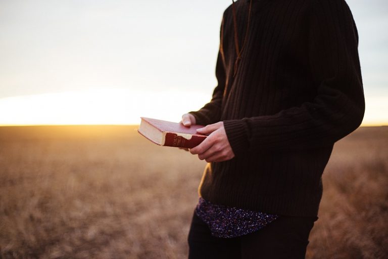 Homem no campo segurando o livro com uma mensagem